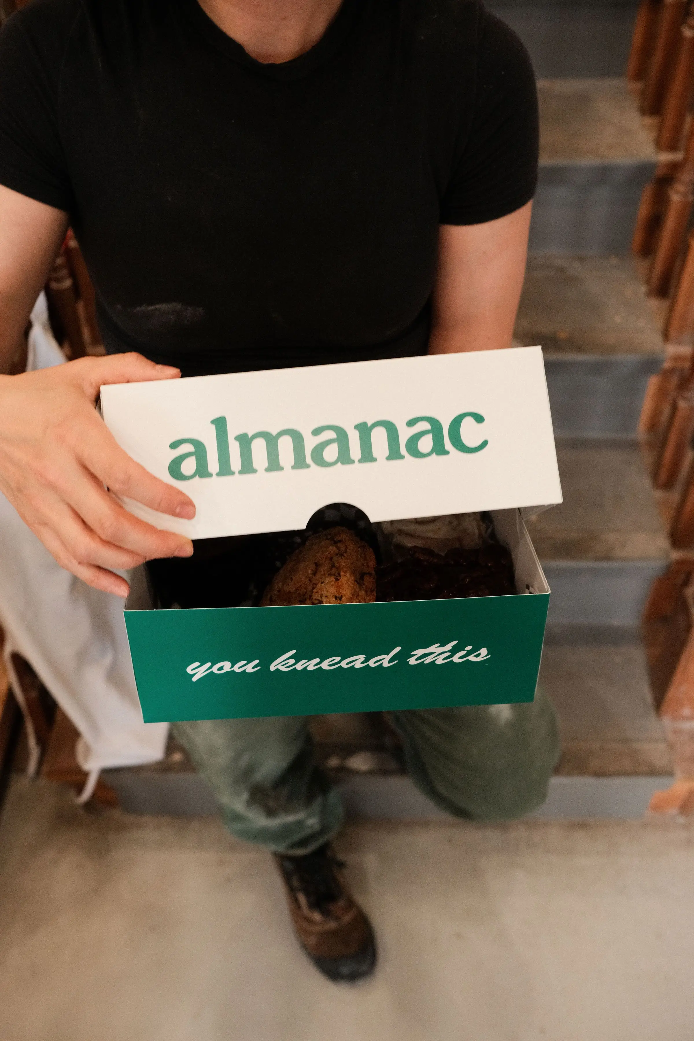 An Almanac box being opened with the 'you knead this' slogan inscribed inside.